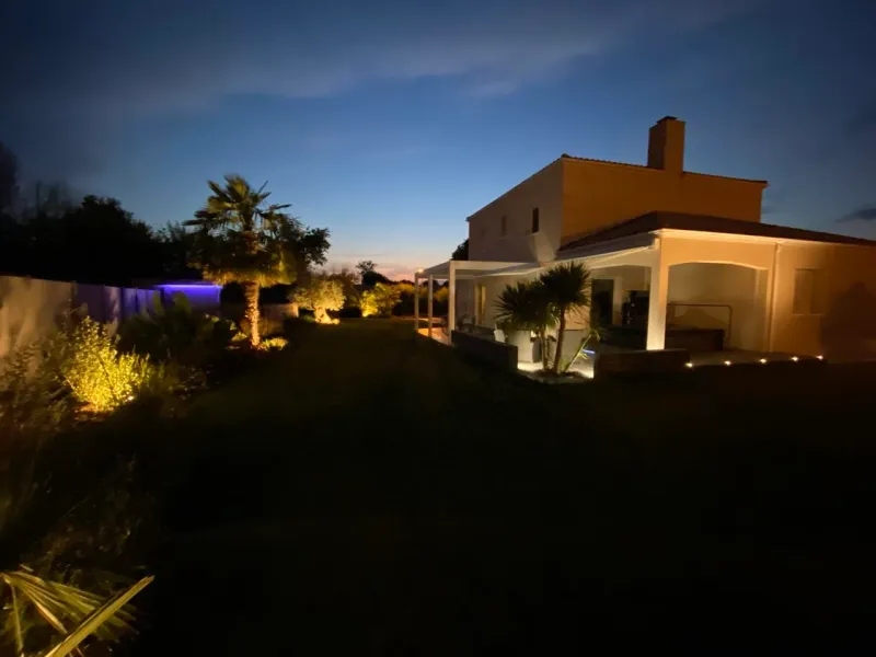Mise en lumière paysagère nocturne — terrasse et palmiers éclairés par AVP